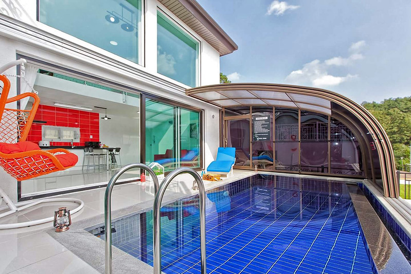A Lean To Wall Mounted Retractable Enclosure Covers a Swimming Pool next to a house
